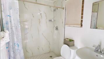 A bathroom with a shower, toilet, and sink.