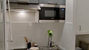 Cocina compacta con lavamanos, estufa y microondas.