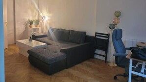 Una sala de estar moderna con un sofá modular, una mesa de centro de vidrio y una silla de escritorio azul.