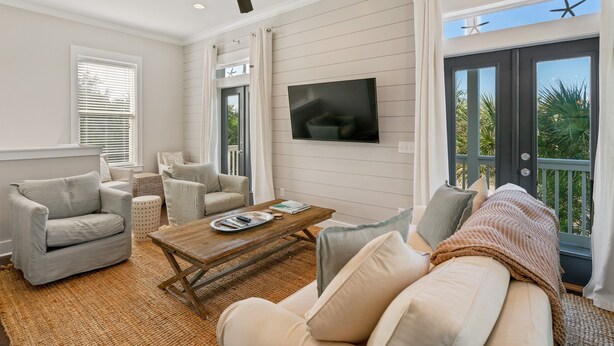 A living room with a ceiling fan, a flat-screen TV, a coffee table, and a sofa.