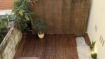 Un pequeño patio con terraza de madera, una piscina pequeña y un césped verde.