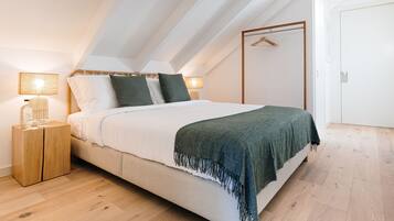 Un dormitorio con cama, mesitas de noche, un armario y una percha.