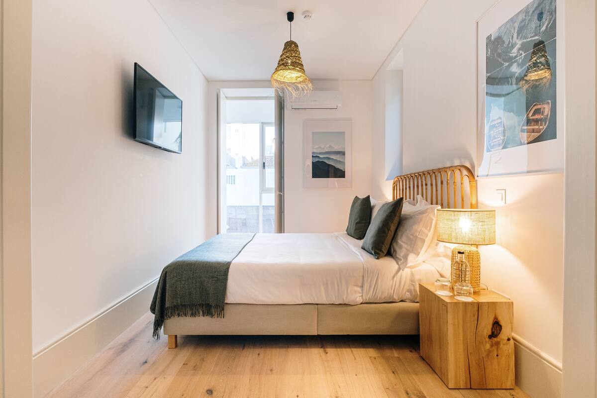 Ein modernes Schlafzimmer mit Bett, Nachttischlampe und Bildern an den Wänden.