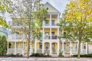 A two-story building with a balcony on the second floor, a front porch, and a garage.