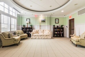 A room with a large sofa, two armchairs, and a bookshelf.
