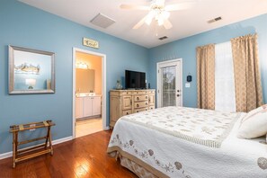 A bedroom with a bed, a dresser, a television, and a ceiling fan.