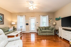 A living room with a ceiling fan, two couches, a television, and a cabinet.