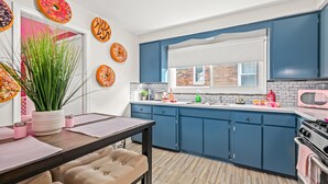 Una cocina moderna con armarios azules, encimera de madera y microondas rosa.