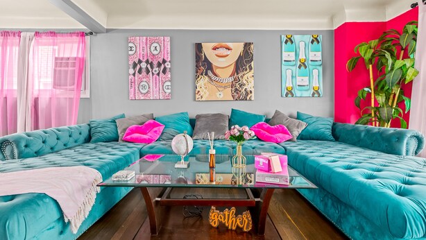 Un sofá color aguamarina con una mesa de centro de cristal, un globo terráqueo y objetos decorativos sobre la mesa.