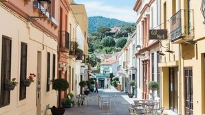 A narrow street lined with buildings, outdoor seating, and a sign for 'Cal Mark'. - Costa Maresme 20 km BCN, Garden apartment & Private pool (Cabrils)