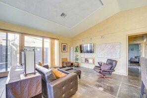 Un salón amplio con un gran ventanal, un televisor de pantalla plana, un sofá, una silla y una mesita de centro.