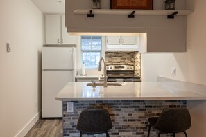 A modern kitchen with a central island, a built-in oven, and a refrigerator.