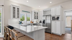 Una cocina moderna con armarios blancos, electrodomésticos de acero inoxidable y una isla central.