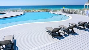 Zona de piscina con sillas de descanso y vista al océano.