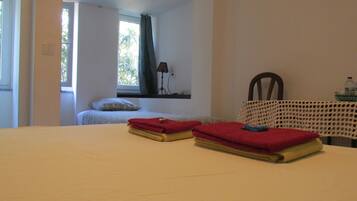 Una habitación con cama, una mesa con mantel de ganchillo y una ventana con cortinas.