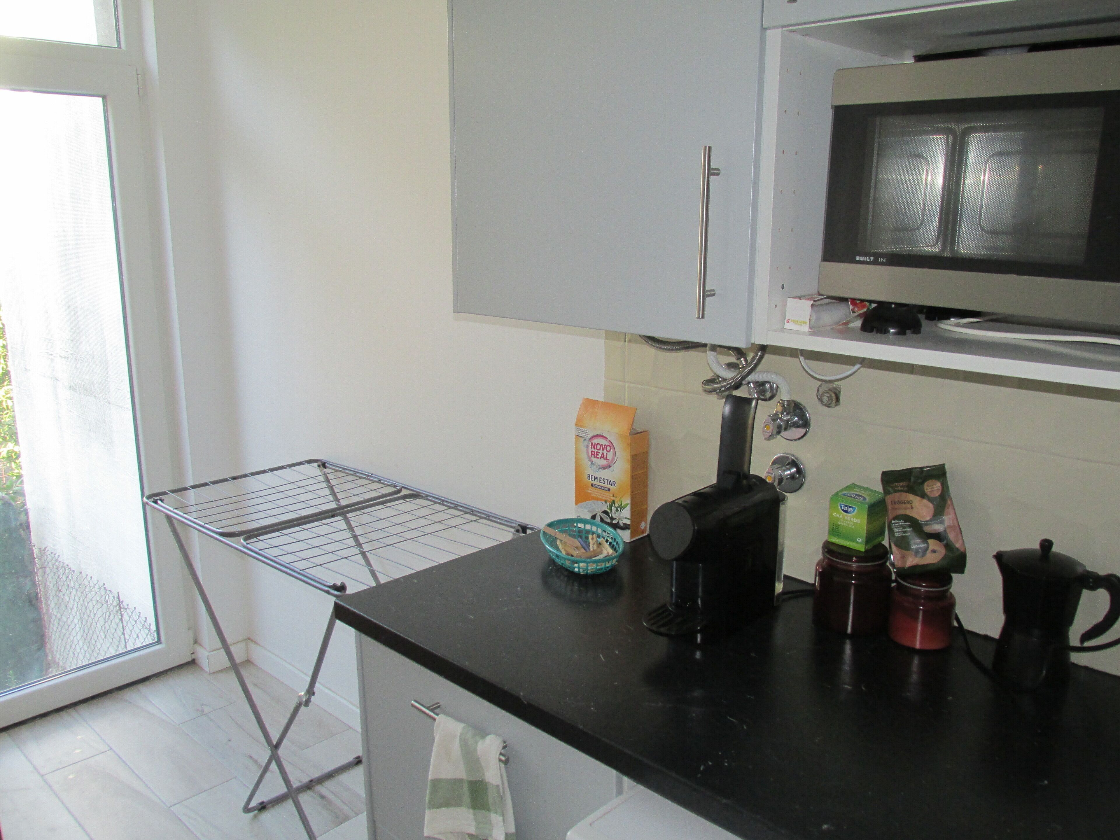 Una cocina equipada con microondas, cafetera y un escurreplatos.