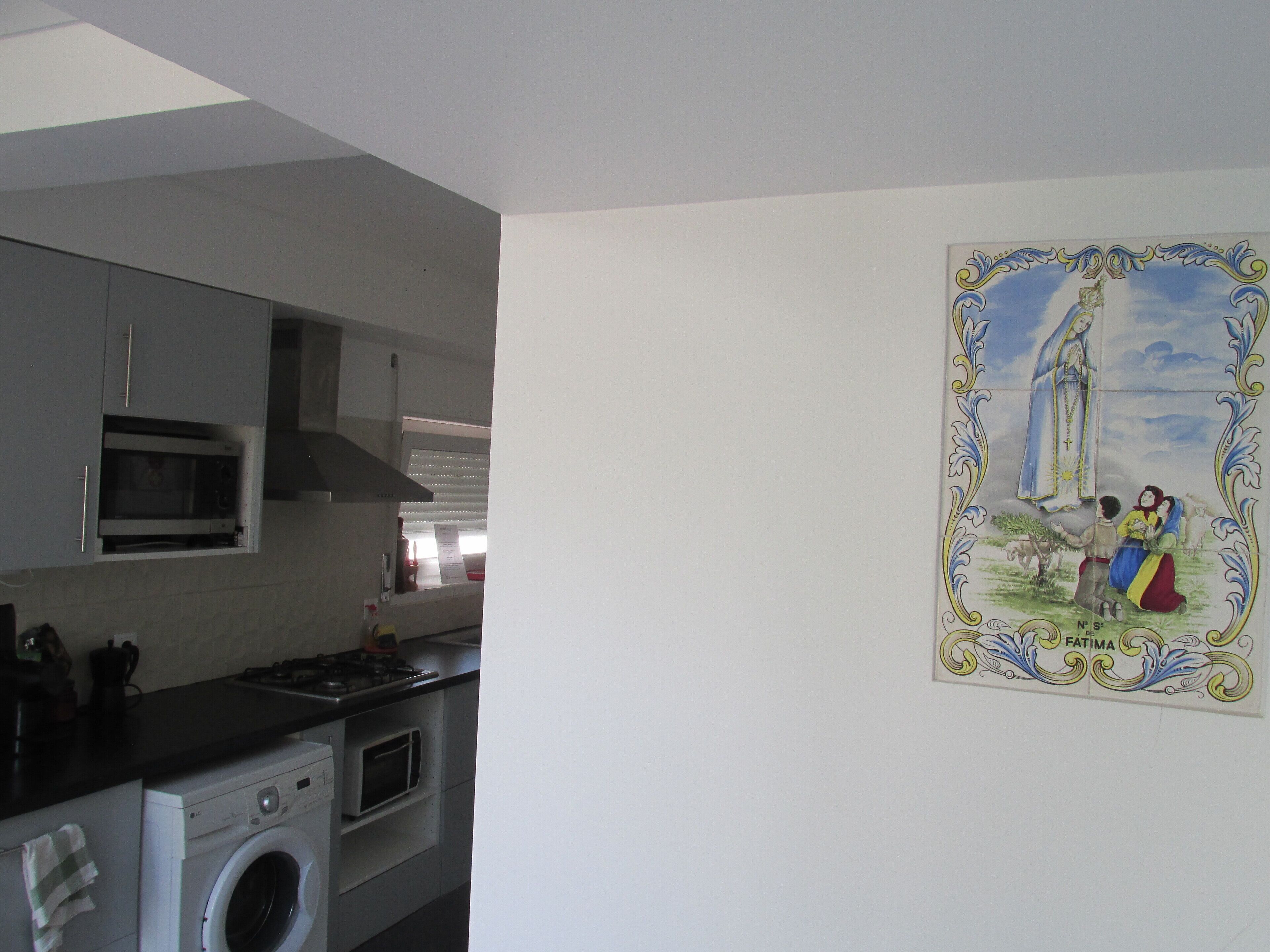 Een keuken met een magnetron, oven en wasmachine.