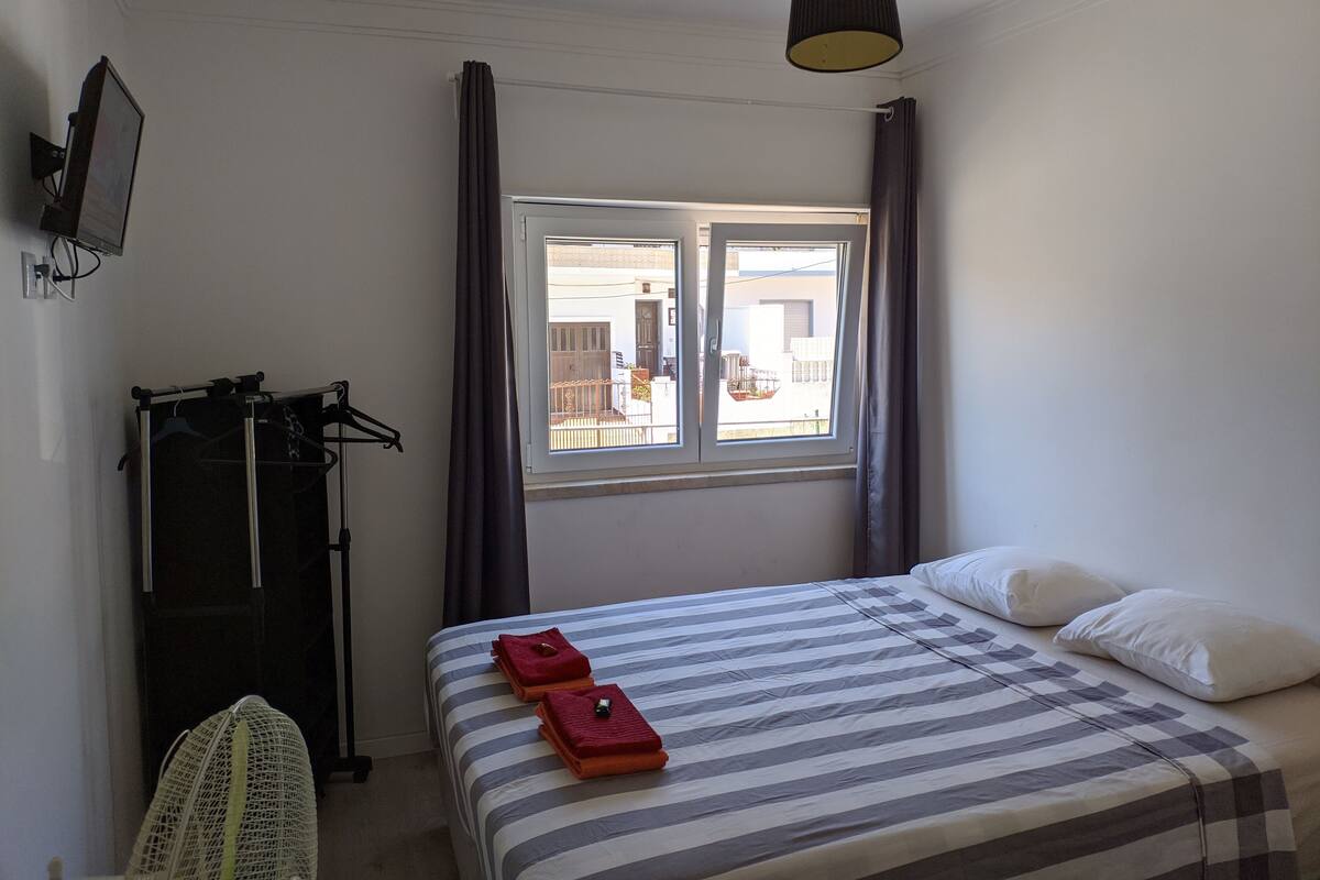 Een hotelkamer met een bed, een raam, een televisie en een droogrek.