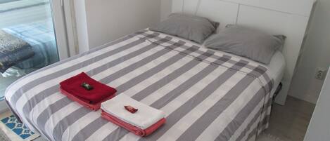 Ein Bett mit gestreifter Bettwäsche, ein rotes und weißes Handtuch sowie eine Lampe auf dem Nachttisch.