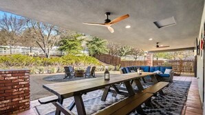 An outdoor patio with a wooden table and benches, surrounded by a brick wall and a patterned rug. - Spacious 4BR RanchHome w/2FirePits (Atascadero)