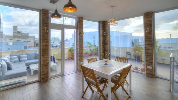 A spacious balcony with a dining area, large windows, and a city view. - Spectacular spacious house with sun terrace ILJU1-1 (Sliema)