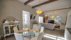 A modern kitchen with a dining area, featuring a glass table, white chairs, and a chandelier. - Spectacular spacious house with sun terrace ILJU1-1 (Sliema)
