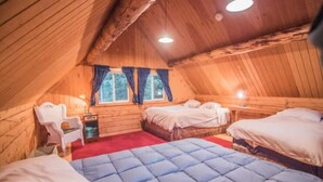 A cozy attic bedroom with wooden walls, two beds, a red carpet, and a window with curtains. - Joy's Kenai River Cabins (Sterling)