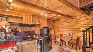 A wooden cabin interior with a kitchen, dining area, and a staircase. - Joy's Kenai River Cabins (Sterling)