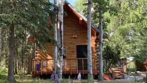 A log cabin surrounded by trees and wildflowers. - Joy's Kenai River Cabins (Sterling)