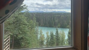 A window with a view of a forest and a lake. - Joy's Kenai River Cabins (Sterling)