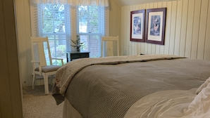 A bedroom with a large bed, a ceiling fan, and a window with blinds.