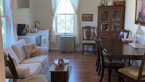 A cozy living room with a white sofa, wooden coffee table, and a dining area with a wooden table and chairs.