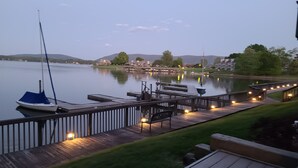 Un molo sul lago con una barca a vela, passerelle di legno e edifici in lontananza.