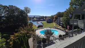 Un quartiere residenziale con piscina circondata da un pontile in legno, vista su un lago e una montagna sullo sfondo.