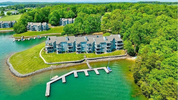 Un resort sul lago con diversi edifici, un molo e un prato curato.