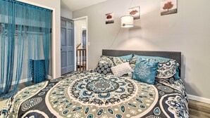 A bedroom with a large bed, a headboard, and a window with blue curtains. - 14 Mi to Frankenmuth: Apt on 3 Acres in Clio! (Clio)