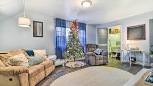 A living room with a beige sofa, a brown armchair, a Christmas tree, and a white console table with a lamp. - 14 Mi to Frankenmuth: Apt on 3 Acres in Clio! (Clio)