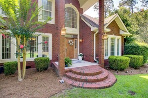 A brick house with a front porch, a wooden door, and a wreath on the door.