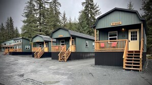 Een rij houten bungalows met wenteltrappen en balkons, genaamd 'Mt Benson', met op de achtergrond hoge bomen.