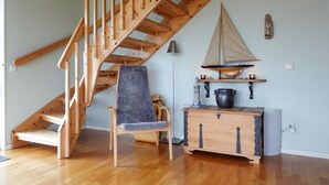 Eine Holztreppe, ein Stuhl, ein kleiner Tisch mit einem Segelbootmodell und eine Lampe.