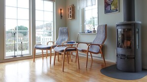 Ein Zimmer mit großen Fenstern, einem Kamin und zwei Sesseln.