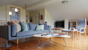 Ein modernes Wohnzimmer mit einem grauen Sofa, einem runden Couchtisch und Holzboden.