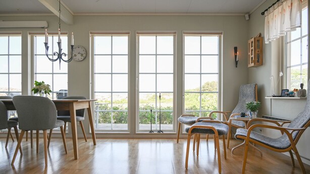 Ein geräumiges Zimmer mit großen Fenstern, Holzboden und einer Essecke mit Stühlen und Tisch.