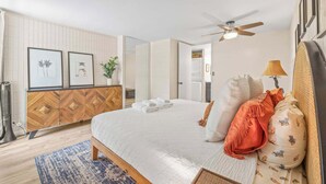 Un dormitorio amplio con una cama grande, un ventilador de techo y un armario de madera.