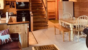 Un intérieur de chalet chaleureux comprenant une cuisine, un coin repas et un escalier menant à un niveau supérieur.