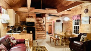 Un intérieur de chalet chaleureux comprenant une cuisine, un coin repas et un espace salon.