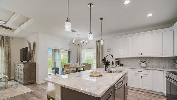 A modern kitchen with white cabinets, a marble island, and pendant lighting. - South West Family Home , 3 Bedroom 2 Bath, King bed suite, 4 Beds , 6 Guests  (Rotonda West)