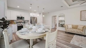A modern kitchen with white cabinetry, stainless steel appliances, and a dining area set for four. - South West Family Home , 3 Bedroom 2 Bath, King bed suite, 4 Beds , 6 Guests  (Rotonda West)