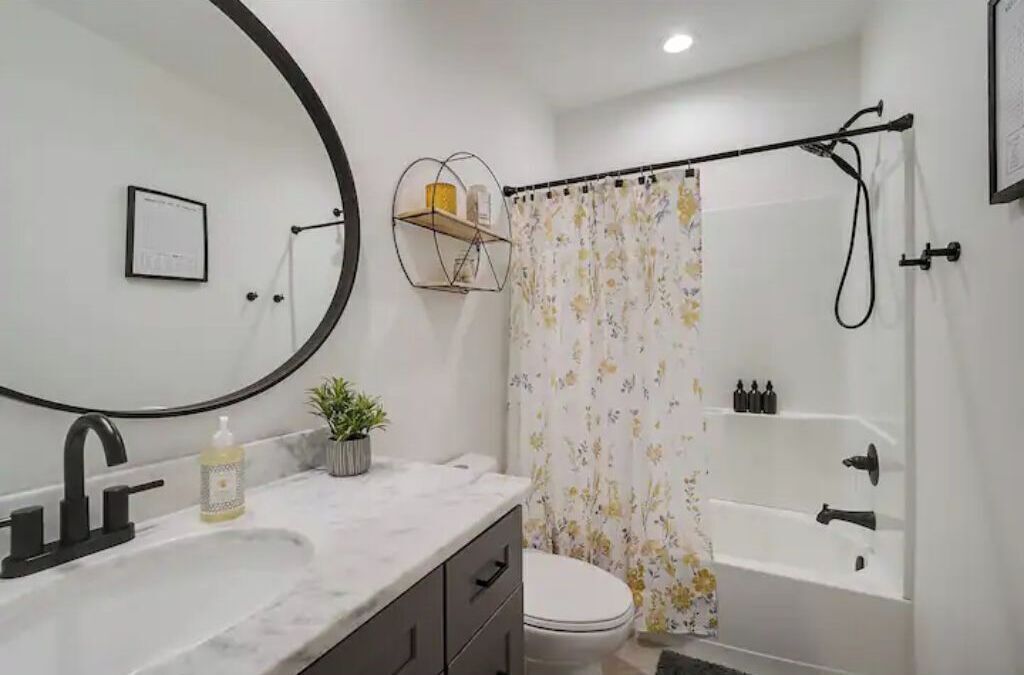 A bathroom with a white sink, a mirror, a toilet, and a bathtub.
