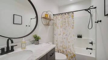 A bathroom with a white sink, a mirror, a toilet, and a bathtub.